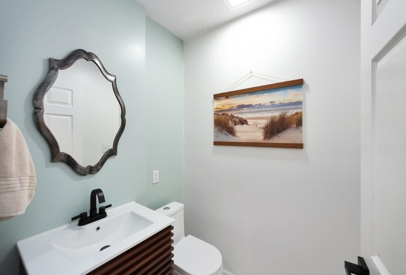 Bathroom vanity with a white rectangular sink, matte black faucet, and slatted wood-finish cabinetry