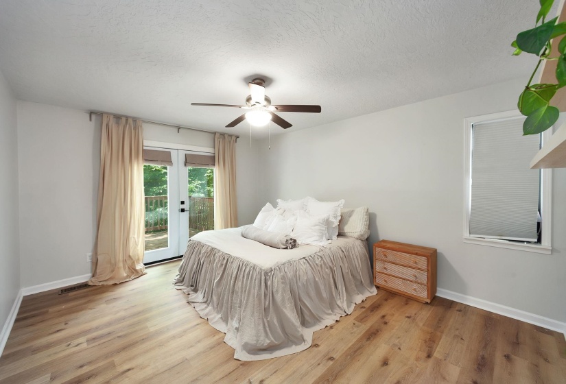 Bright interior space featuring wood-finish flooring, a ceiling fan with integrated lighting, and a white window with blinds