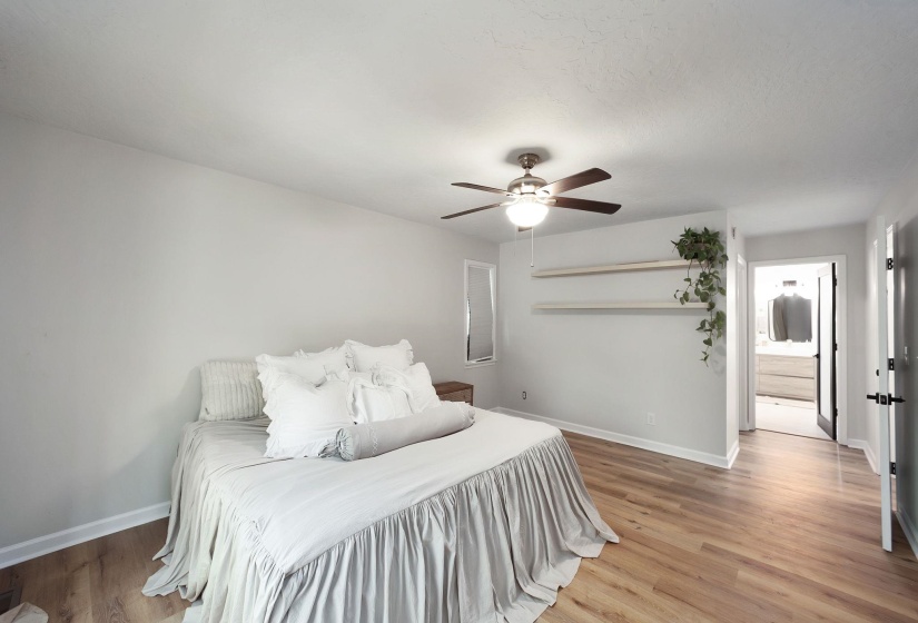 Spacious room with wood-finish flooring, ceiling fan, and white baseboards
