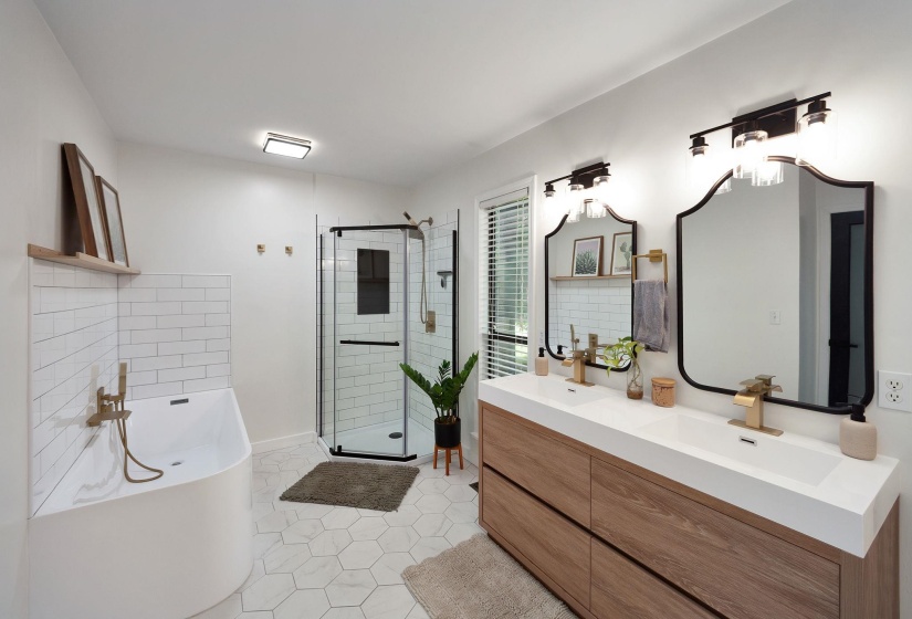 Bathroom featuring a freestanding soaking tub with subway tile surround, corner shower with glass enclosure, dual vanity with undermount sinks and wood-finish cabinetry, and hexagon tile flooring