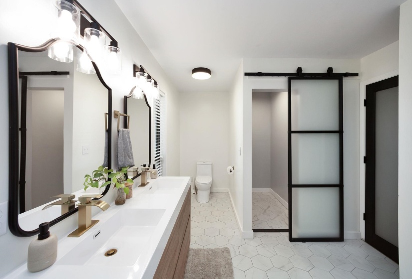 Modern bathroom featuring a dual vanity with rectangular sinks and gold-finish faucets