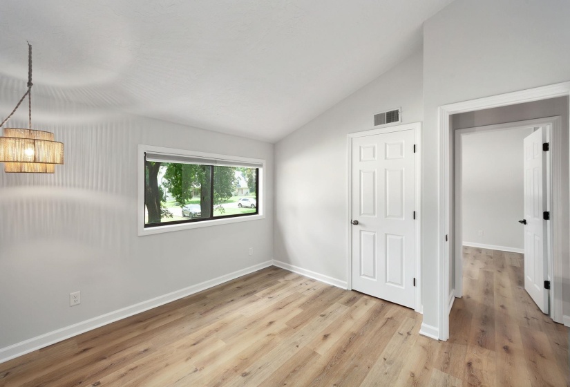 Vaulted ceiling room featuring light wood-finish flooring, a contemporary drum pendant light fixture, and white painted trim