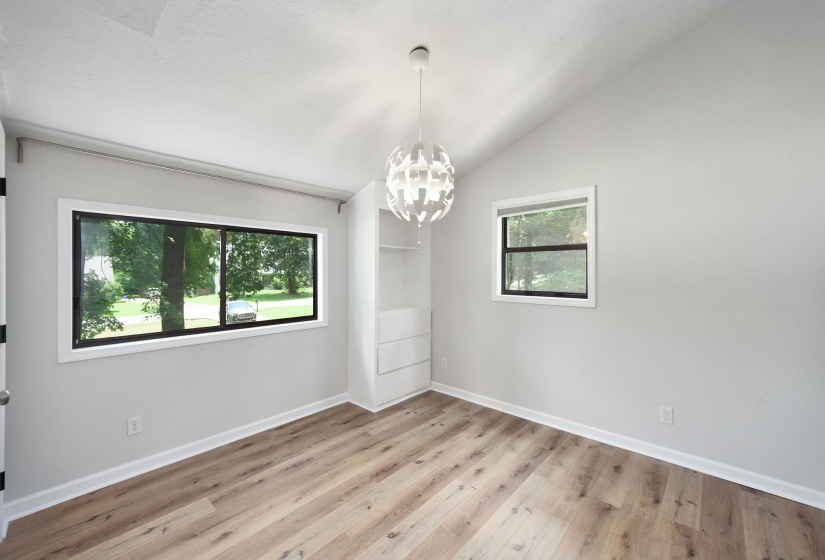 Interior room featuring wood-finish flooring, light gray walls, and an angled ceiling