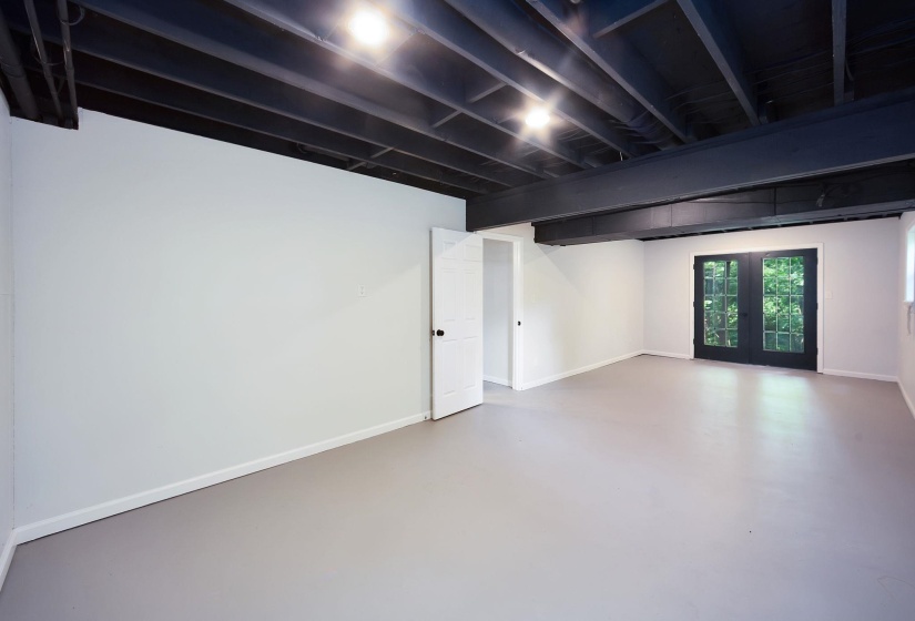 Finished room with a painted exposed ceiling, recessed lighting, double French doors, and light-colored flooring