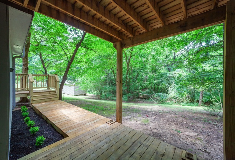 Covered outdoor patio with wood-finish decking and exposed beam ceiling