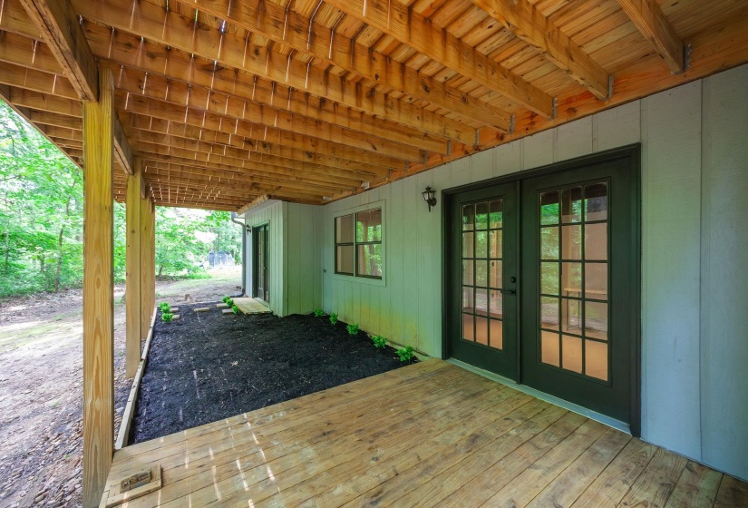 Expansive covered porch with wood flooring and exposed wood ceiling beams