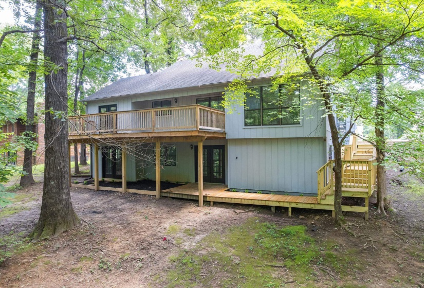 Two-story residence featuring a spacious upper-level wood deck and a ground-level wood patio