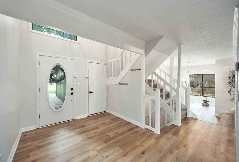 Entryway featuring high ceilings, wood-finish flooring, and a white staircase with carpeted treads