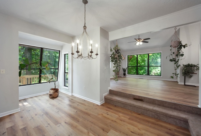 Expansive room featuring wood-finish flooring, large picture windows, a multi-tiered ceiling, and recessed lighting