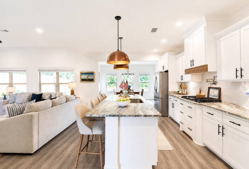 Kitchen featuring a large island with stone countertop, white shaker cabinetry, stainless steel appliances, and wood-finish flooring