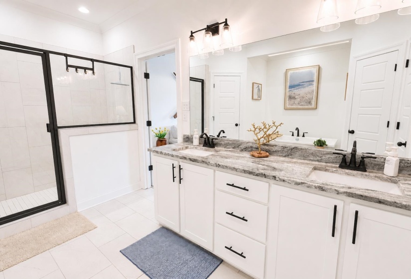 Dual vanity with white cabinetry, black hardware, and a patterned stone countertop