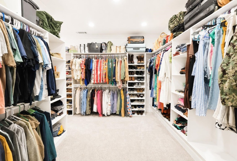 Spacious walk-in closet featuring extensive built-in shelving, multiple hanging rods, dedicated shoe storage, recessed lighting, and carpet flooring