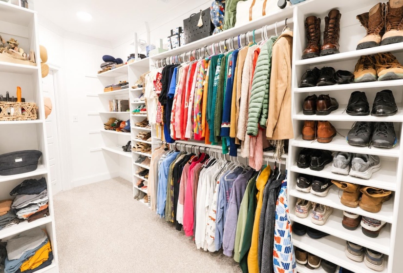 Walk-in closet featuring built-in white shelving, multiple hanging rods, and recessed lighting