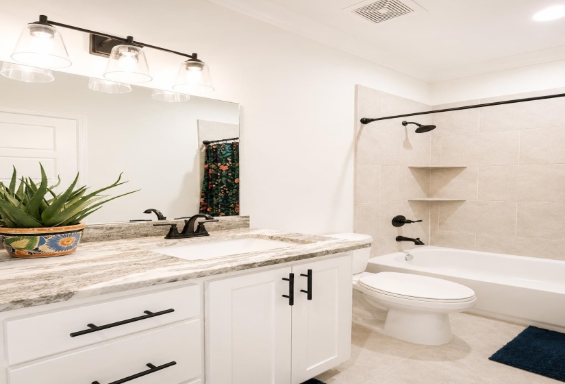 Modern bathroom featuring a single vanity with a stone-finish countertop, undermount sink, and black hardware