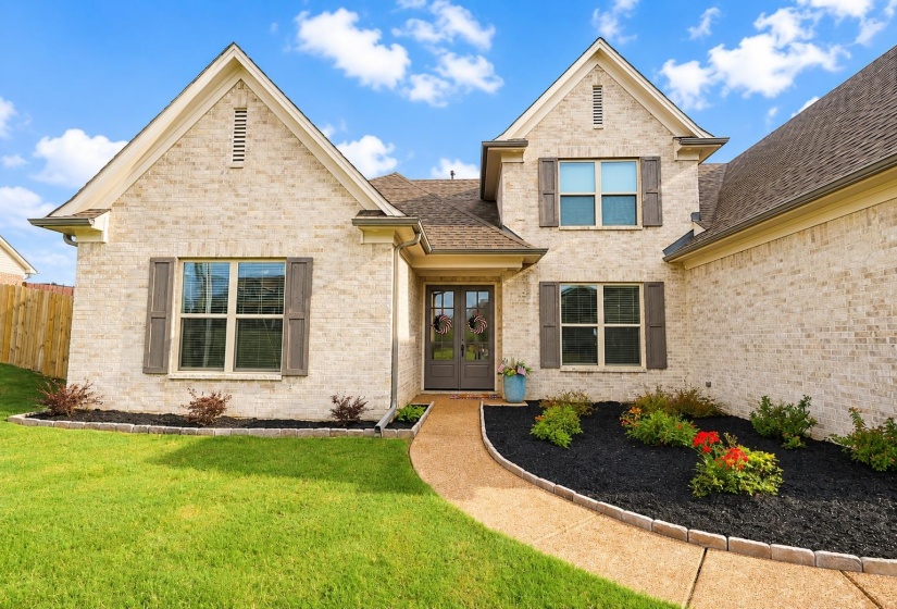 Traditional-style home featuring light-colored brick veneer, dark brown shutters, and a prominent front entry with double doors