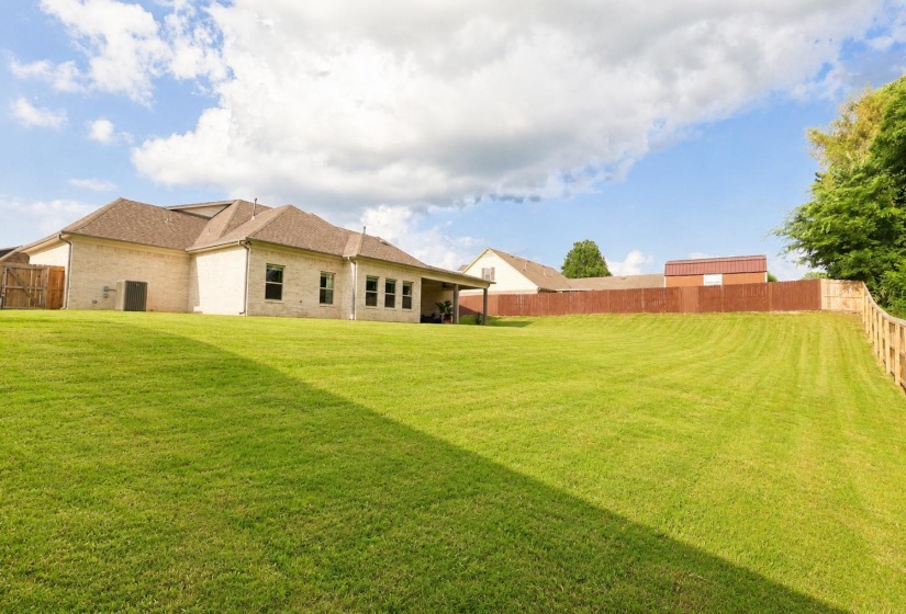 Expansive backyard featuring a manicured lawn and a privacy fence