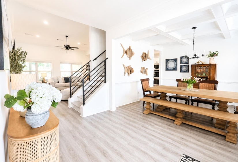 Spacious dining area featuring a coffered ceiling, wood-finish flooring, and a large dining table with benches