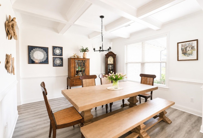 Spacious room featuring coffered ceilings, light wood-finish flooring, and white wall paneling