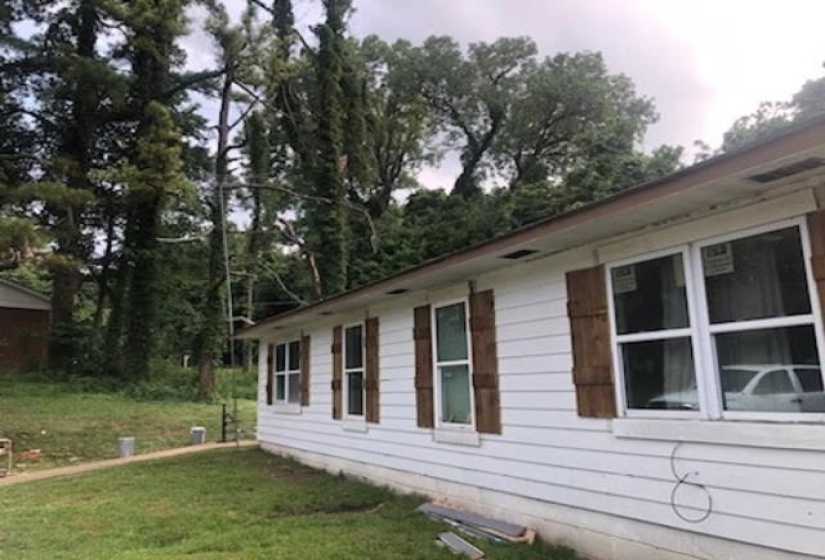 White siding exterior featuring multiple windows with dark wood-tone shutters