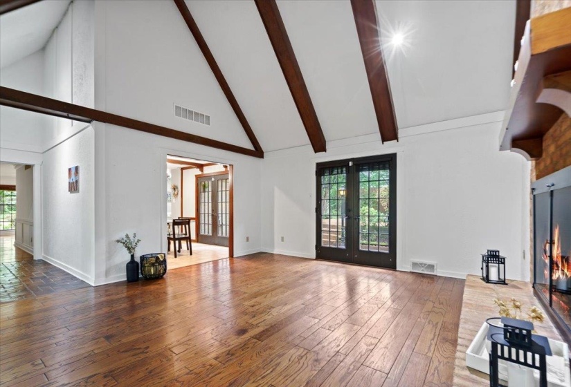 Unfurnished living room featuring visible vents, high vaulted ceiling, hardwood / wood-style flooring, and french doors