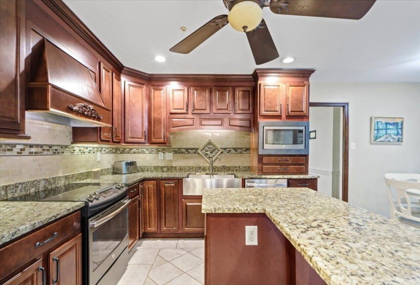 Kitchen with a sink, decorative backsplash, custom exhaust hood, a ceiling fan, and appliances with stainless steel finishes