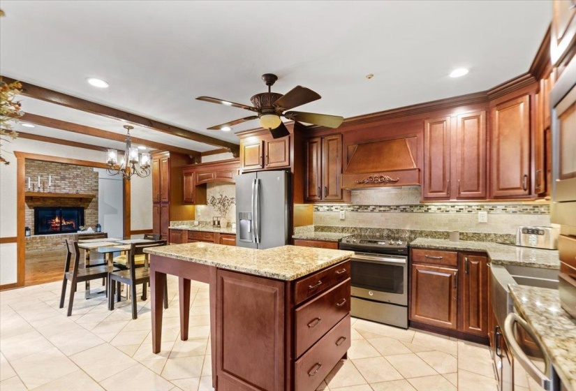 Kitchen featuring tasteful backsplash, ceiling fan with notable chandelier, custom range hood, and appliances with stainless steel finishes