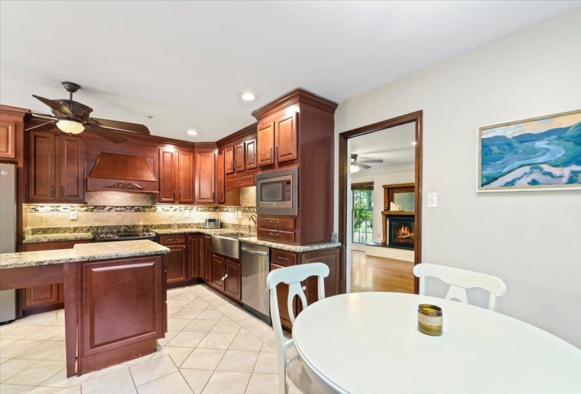 Kitchen featuring a sink, appliances with stainless steel finishes, ceiling fan, custom exhaust hood, and backsplash