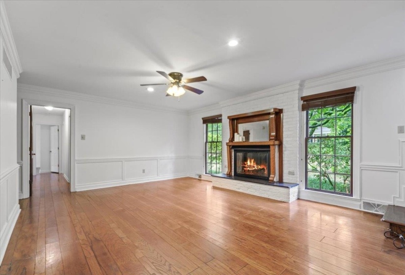 Unfurnished living room with hardwood / wood-style floors, ceiling fan, a decorative wall, and crown molding