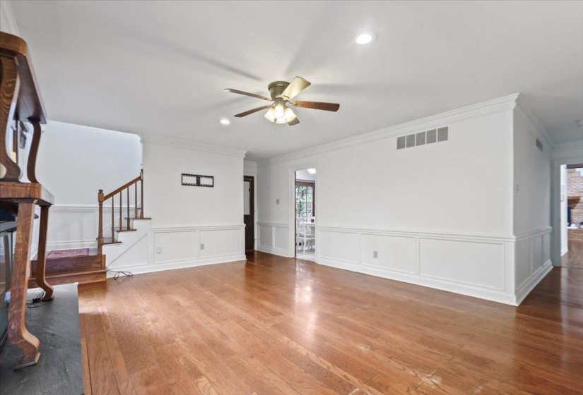 Unfurnished living room with ornamental molding, visible vents, ceiling fan, and light wood-style floors