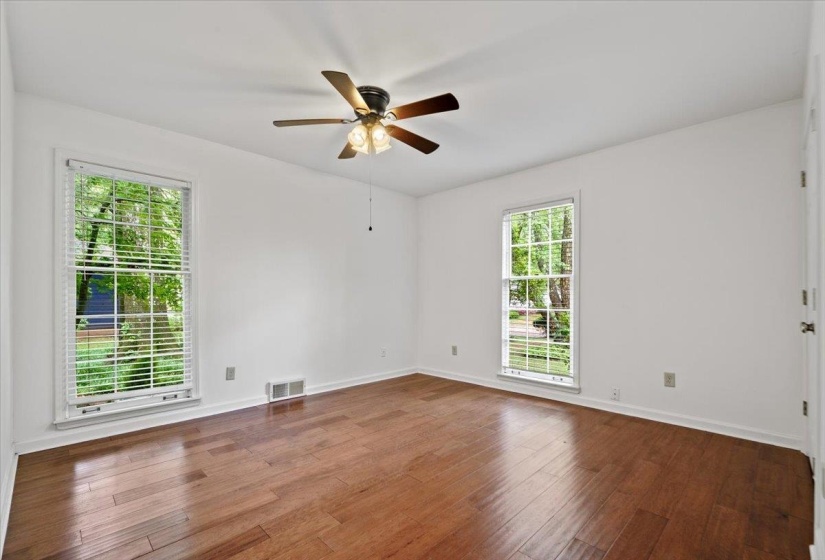 Unfurnished room with baseboards, visible vents, wood finished floors, and ceiling fan