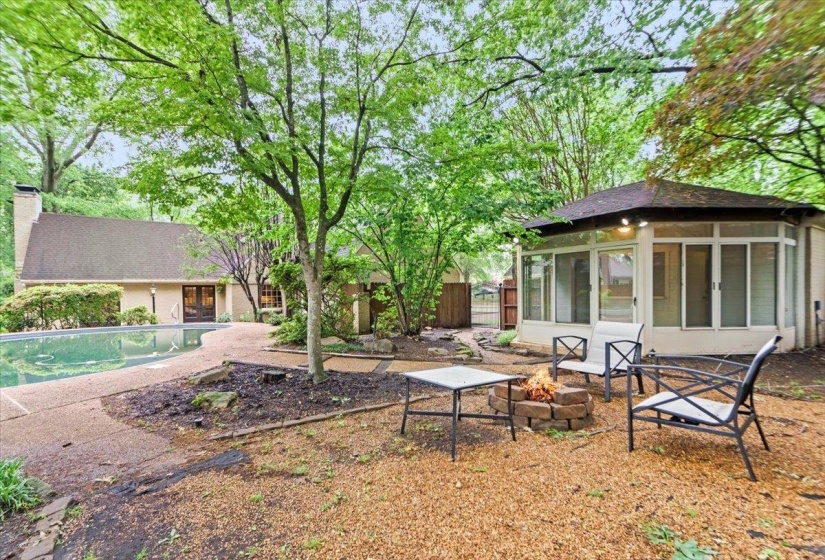 View of yard featuring a fire pit, fence, a sunroom, a patio area, and an outdoor pool