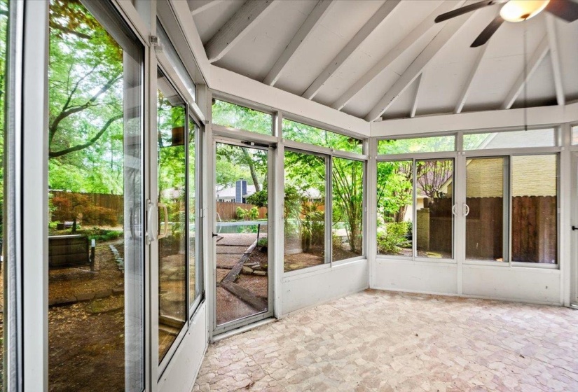 Unfurnished sunroom with beamed ceiling and ceiling fan
