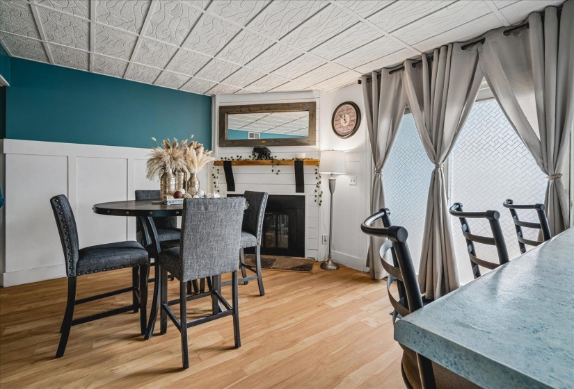 Dining area featuring wood-finish flooring, a fireplace with a wood mantel, and wainscoting
