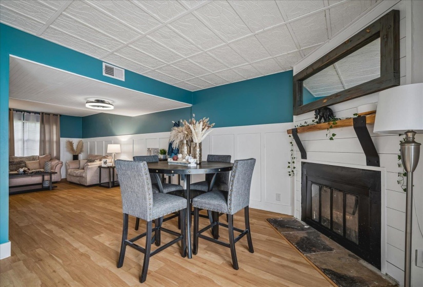 Living area featuring wood-finish flooring, a fireplace with a stone hearth, and white shiplap paneling