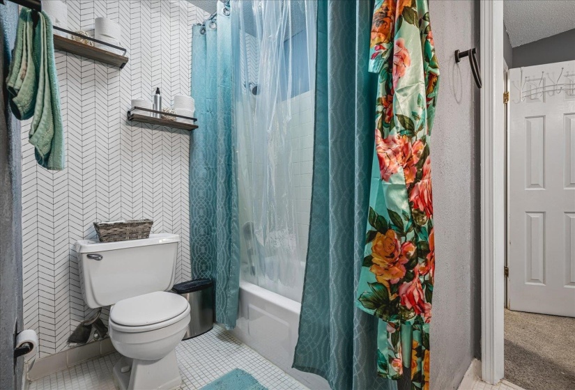 Bathroom featuring white herringbone pattern wall tile and white floor tile