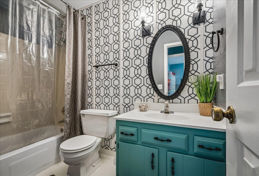 Bathroom featuring a teal vanity with an integrated sink, an oval mirror, and wall-mounted sconces