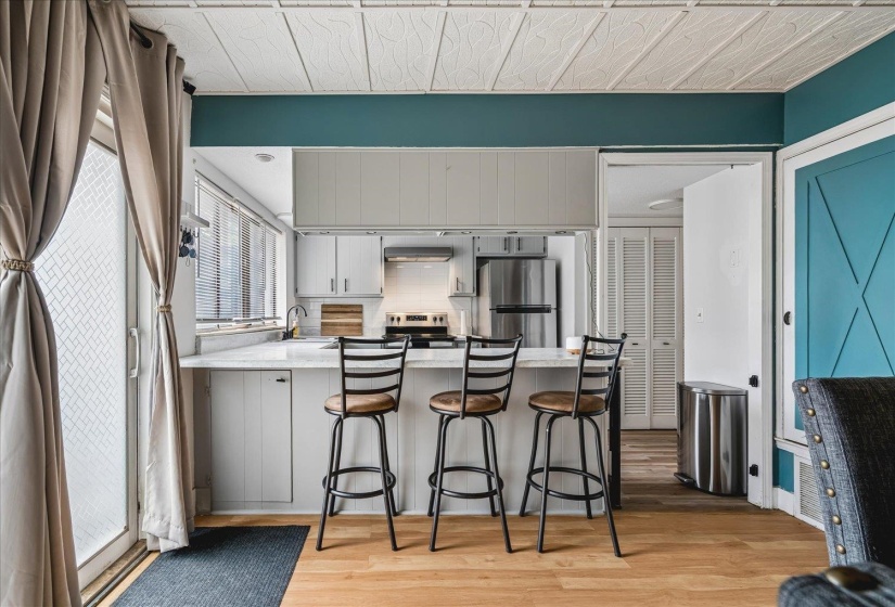 Kitchen featuring white cabinetry, stainless steel appliances, and a light-colored countertop with an integrated breakfast bar