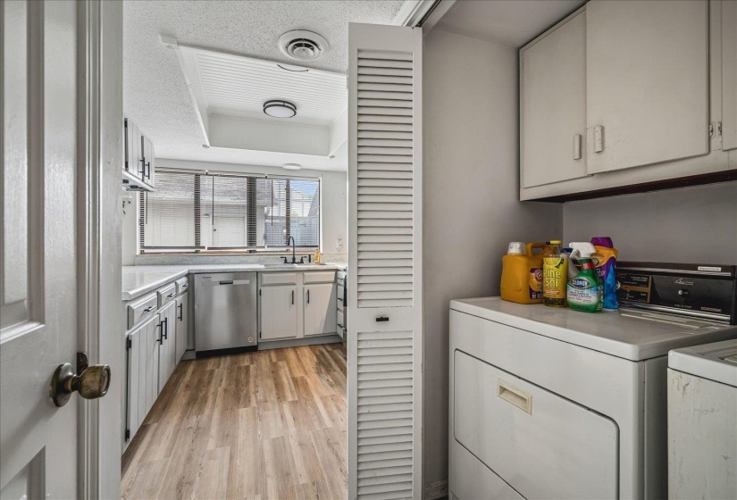 Kitchen with wood-finish flooring, white cabinetry, and stainless steel dishwasher