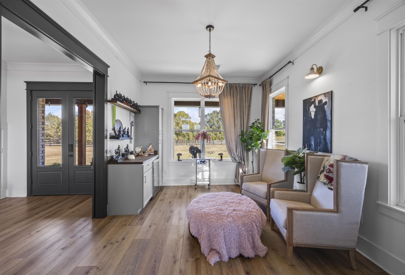 Spacious room featuring wide plank wood-finish flooring and a built-in wet bar with cabinetry