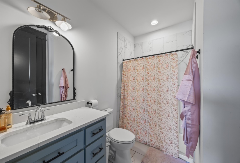 Bathroom featuring a vanity with a white countertop, an undermount sink, and blue cabinetry with black hardware