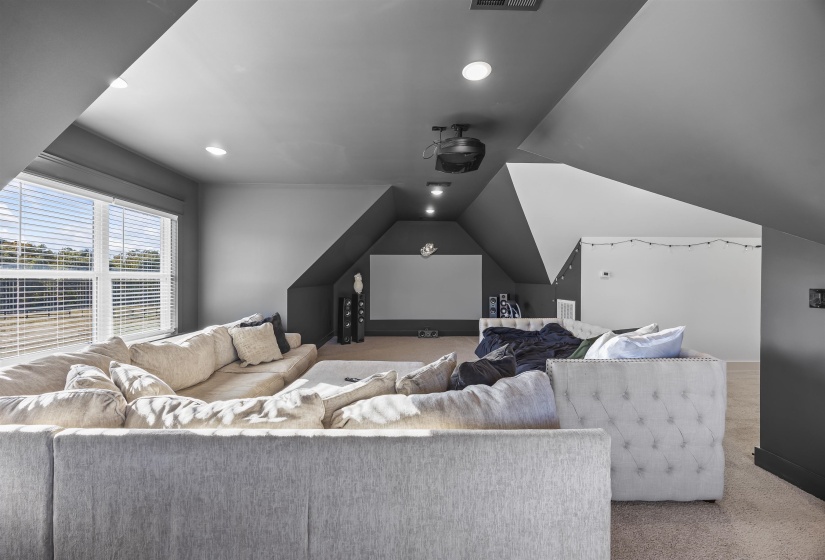 Carpeted bonus room with neutral wall tones and sloped ceilings
