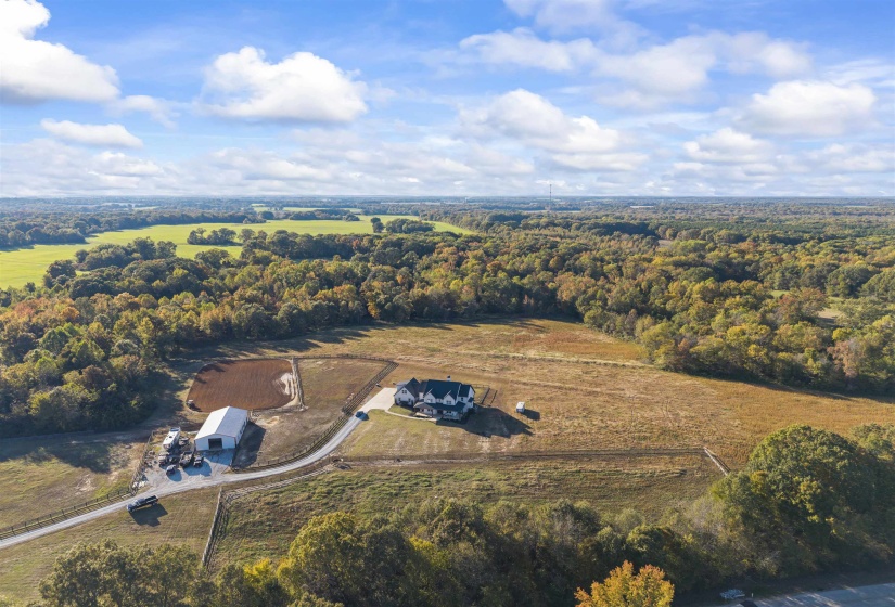 Expansive rural property featuring a large residence, separate barn structure, and an outdoor arena