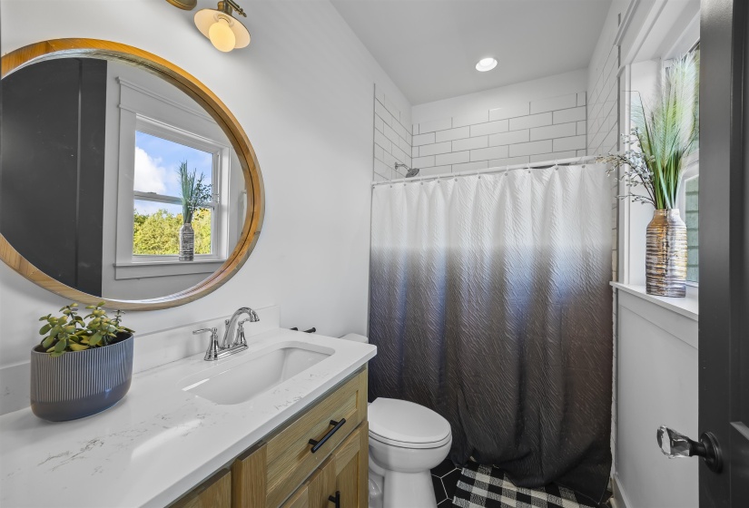Bathroom featuring a wood-finish vanity with a white countertop and integrated sink, chrome faucet, and a round wood-framed mirror