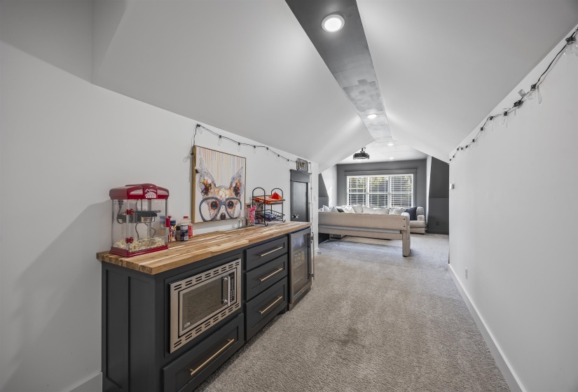 Custom built-in cabinetry with a wood-finish countertop, integrated microwave, and beverage refrigerator