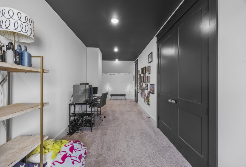 Carpeted hallway featuring a dark ceiling with recessed lighting