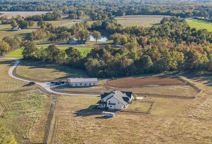 Expansive rural property featuring a main residence, fenced paddocks, a large outbuilding, and a winding gravel driveway
