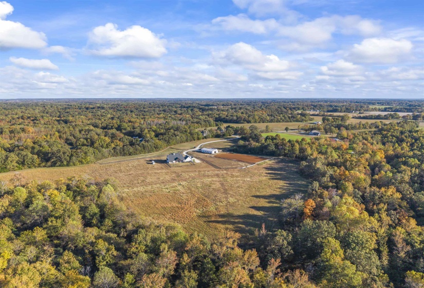 Expansive property featuring a contemporary residence, additional outbuildings, and a gravel driveway