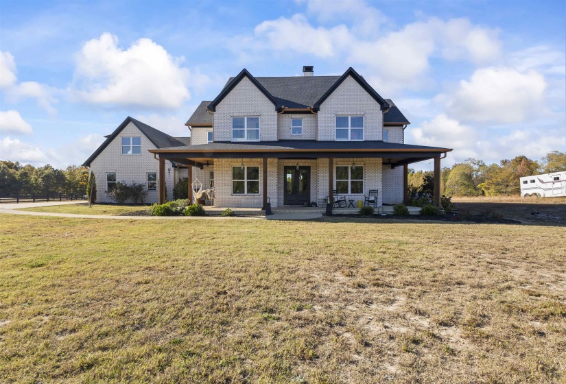 Two-story brick exterior with a covered front porch featuring dark wood columns and a black roof