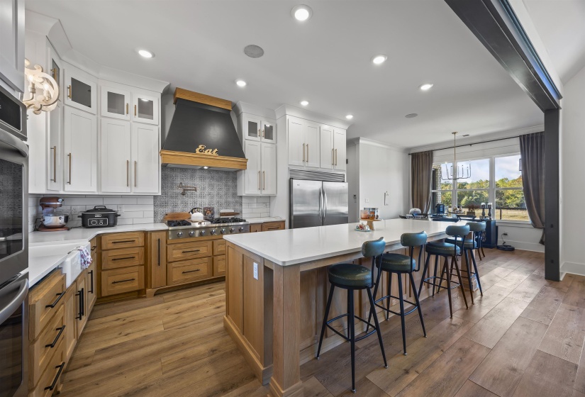 Modern kitchen with wood-finish flooring and a large island featuring a white countertop and seating for four