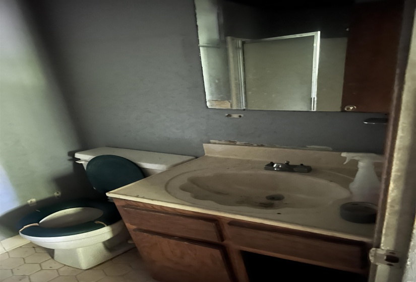 Bathroom featuring a white toilet, wood-finish vanity with an integrated sink, and a mirrored medicine cabinet